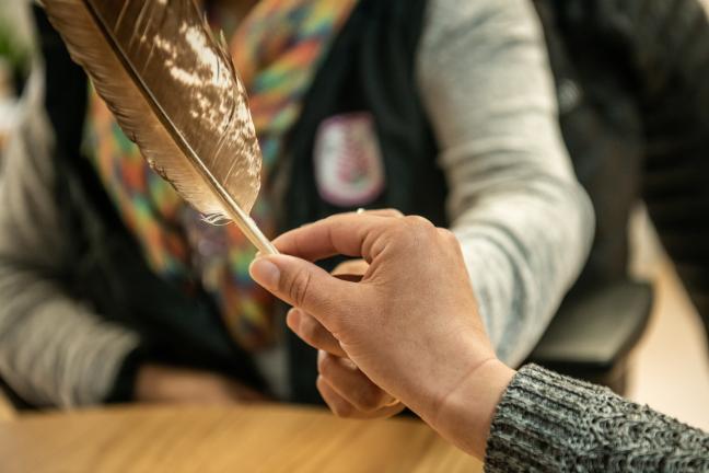 A member of the First Nations Health Programs team passes a talking feather to a coworker. 
