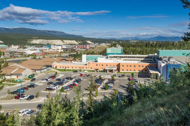 Whitehorse General Hospital and parking lot on a sunny day. 