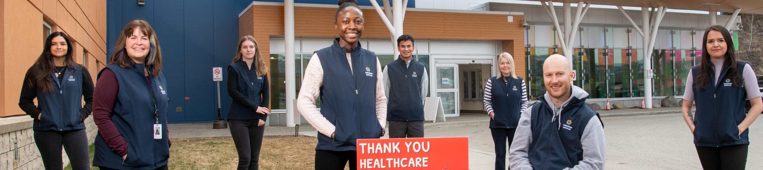Members of the Whitehorse General Hospital Volunteer Services Team pose outside the hospital. 